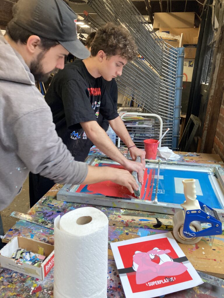 Adult and high school student work on a screen print together.