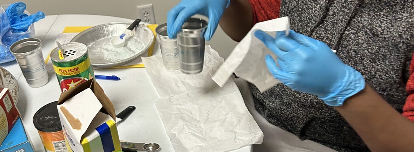 Student wearing googles works on chemistry experiment at a round table.