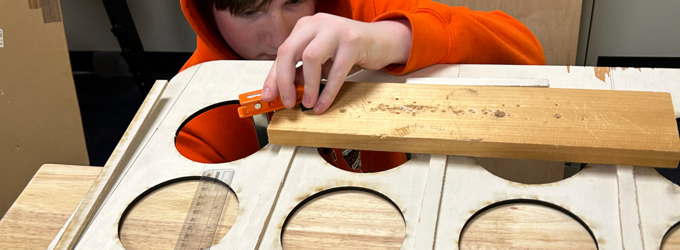 student works on woodworking project, carefully clamping two boards